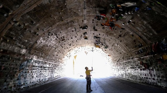 Unik, Bekas Terowongan 'Disulap' Jadi Arena Panjat Dinding David Sanchez, 18, climbs helped by Carlos Gallardo, 65, at the wall of the Foixarda tunnel, which was transformed from a former road tunnel into an urban, free-to-use climbing gym open at all times, equipped with thousands of holds, in Barcelona, Spain June 26, 2024. REUTERS/Nacho Doce