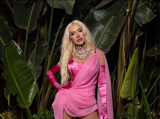 Dalam penampilan lainnya, Aguilera mengenakan tanktop putih dengan celana jeans. Tampak tubuhnya semakin mungil dengan pinggang yang kecil. Dia berpose sambil memegan produk seks dari brand miliknya, Intimacy Justice. Dalam keterangan foto tersebut, Christina menulis, Talk Dirty To Me, diikuti dengan emoji lipstik merah. Foto: dok. Instagram @xtina