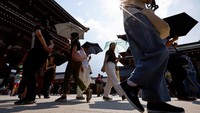 Pejalan kaki yang memegang payung berjalan di bawah sinar matahari yang terik di kuil Sensoji saat pemerintah Jepang mengeluarkan peringatan serangan panas di 39 dari 47 prefektur di Tokyo, Jepang, Senin (22/7/2024).