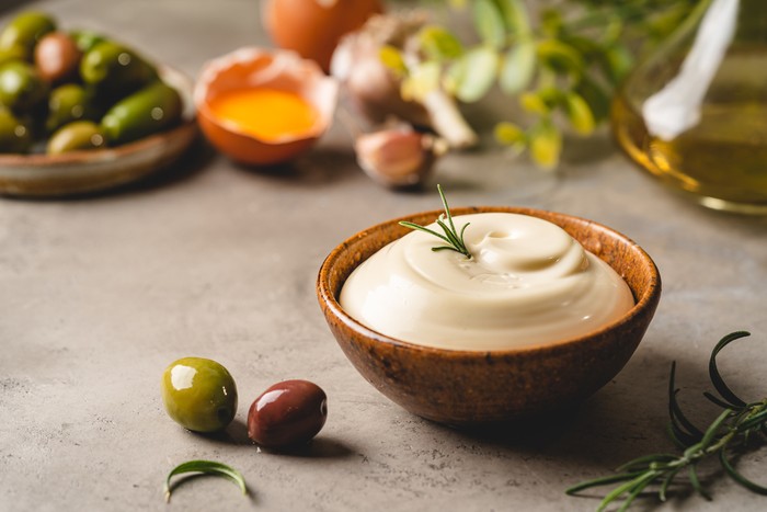 Bowl of Homemade mayonnaise sauce with olives, ingredients and herbs for cooking