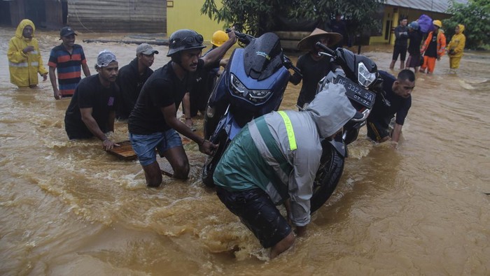 Meraup Cuan dari Banjir Halmahera Tengah Sejumlah warga mengangkut kendaraan roda dua menggunakan rakit saat banjir di Desa Lukolamo, Kabupaten Halmahera Tengah, Maluku Utara, Selasa (23/7/2024). Sebagian warga di daerah itu menawarkan jasa penyeberangan motor untuk melintasi ruas jalan yang terendam banjir luapan Sungai Kobe dengan tarif Rp100 ribu per motor. ANTARA FOTO/Andri Saputra/rwa.