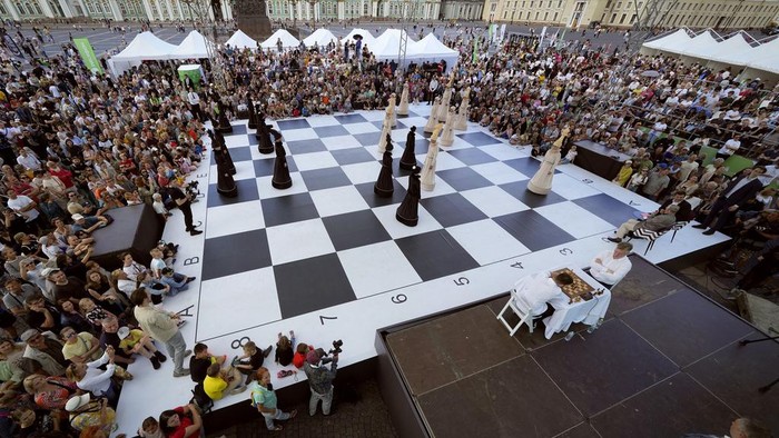 FIDE World Chess 1999 Championship winner Alexander Khalifman, right, and European Individual Chess Championship 2017 winner Maxim Matlakov play a chess game as actors dressed as chess pieces demonstrate this game on a huge сhessboard during the International Chess Day celebration at the Dvortsovaya (Palace) Square in St. Petersburg, Russia, Saturday, July 20, 2024. International Chess Day has been celebrated annually on 20 July since 1966, and it marks the day the International Chess Federation (FIDE) was founded 100 years ago, on 20 July 1924. (AP Photo/Dmitri Lovetsky)