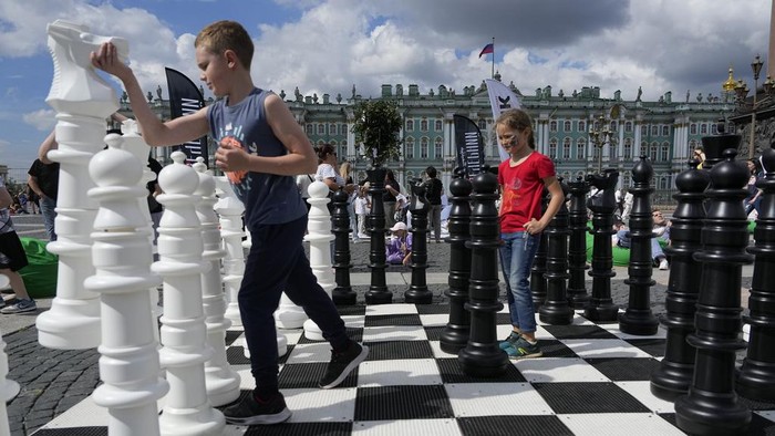 FIDE World Chess 1999 Championship winner Alexander Khalifman, right, and European Individual Chess Championship 2017 winner Maxim Matlakov play a chess game as actors dressed as chess pieces demonstrate this game on a huge сhessboard during the International Chess Day celebration at the Dvortsovaya (Palace) Square in St. Petersburg, Russia, Saturday, July 20, 2024. International Chess Day has been celebrated annually on 20 July since 1966, and it marks the day the International Chess Federation (FIDE) was founded 100 years ago, on 20 July 1924. (AP Photo/Dmitri Lovetsky)