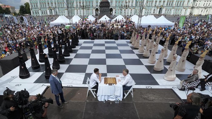 FIDE World Chess 1999 Championship winner Alexander Khalifman, right, and European Individual Chess Championship 2017 winner Maxim Matlakov play a chess game as actors dressed as chess pieces demonstrate this game on a huge сhessboard during the International Chess Day celebration at the Dvortsovaya (Palace) Square in St. Petersburg, Russia, Saturday, July 20, 2024. International Chess Day has been celebrated annually on 20 July since 1966, and it marks the day the International Chess Federation (FIDE) was founded 100 years ago, on 20 July 1924. (AP Photo/Dmitri Lovetsky)