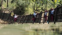 Siswa berusaha melintasi jembatan rusak di Neglasari, Lengkong, Sukabumi, Jawa Barat, Selasa (23/7/2024).