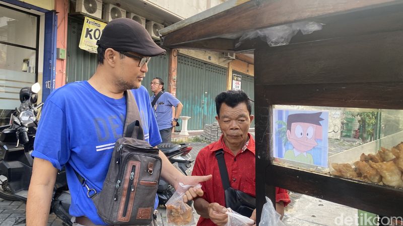 Samiran, penjual bakso mirip karakter kartun Suneo sedang melayani pelanggan.