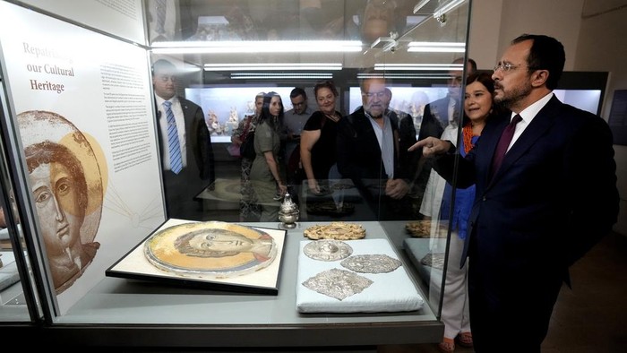Siprus Pamerkan Perhiasan dan Barang Antik Zaman Perunggu yang Pernah Dijarah Cyprus' President Nikos Christodoulides, right, stands in front of an Orthodox Christian icon after the same was repatriated and displayed at the Archeological museum in capital Nicosia, Cyprus, Monday, July 22, 2024. The returned artifacts numbering around 60, including jewelry from the Chalcolithic Period dating between 3500-1500 BC, Bronze Age bird-shaped idols, jars and spearheads as well as many Orthodox Christian icons were part of a larger haul of 250 antiquities that German authorities had seized from Turkish art dealer Aydin Dikmen in 1997. (AP Photo/Petros Karadjias)