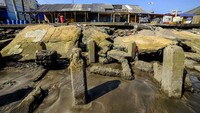 Warga melintas di sekitar dermaga kapal nelayan yang rusak di Teluk Labuan, Pandeglang, Banten, Selasa (23/7/2024).