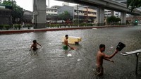 Para pria menyeberang jalan yang banjir menyusul hujan lebat yang disebabkan oleh Topan Gaemi, di Manila, Filipina, Rabu (24/7/2024). Bencana ini mendorong pihak berwenang untuk menghentikan pekerjaan dan kelas, sementara perdagangan saham dan valuta asing ditangguhkan.