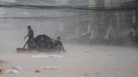 Warga mengarungi air banjir setinggi pinggang di ibu kota Manila, beberapa di antaranya duduk di wadah darurat agar tetap kering, sementara yang lain mengangkutnya melintasi jalan-jalan yang terendam banjir.