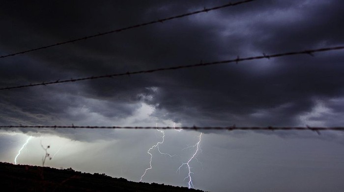 BLACKWELL, OK - MAY 29:  Lighting strikes through a fence and across a field as Tempest Tours storm chase tour guests watch a storm over the Great Plains in the United States of America May 29, 2006 outside of Blackwell, Oklahoma, USA. (Photo by Jeff Hutchens/Getty Images)