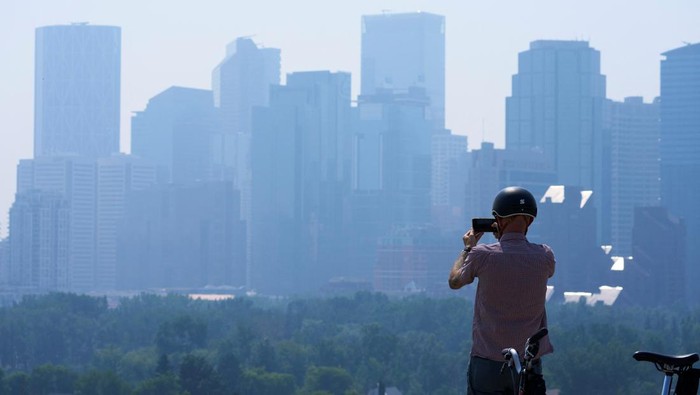 A person jogs as the smoke from wildfires in British Columbia and Alberta blankets the downtown core of Calgary, Alberta, Canada July 24, 2024.  REUTERS/Todd Korol