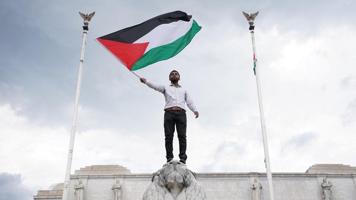 A demonstrator waves the Palestinian flag from the Columbus Memorial Fountain at Union Station during a protest on the day Netanyahu addresses a joint meeting of Congress, in Washington, U.S., July 24, 2024. REUTERS/Seth Herald