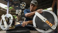 Penyedia jasa penyewaan film untuk layar tancap, Nur Iyan, melakukan perawatan koleksi film seluloid 35mm di Nur Iyan Film, Pamulang, Tangerang Selatan, Banten, Kamis (25/7/2024).