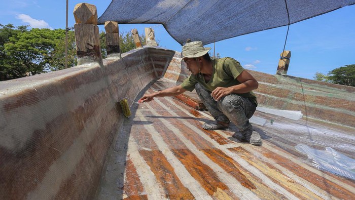 Melihat Pembuatan Kapal Nelayan Tradisional di Aceh Pekerja menyelesaikan pembuatan kapal di kawasan galangan kapal nelayan Gampong Jawa, Banda Aceh, Aceh, Kamis (25/7/2024). Menurut pelaku usaha galangan kapal tradisional, pembuatan kapal nelayan berkapasitas 20-30 gross ton (GT) dengan biaya ratusan juta rupiah hingga miliaran rupiah itu membutuhkan waktu pengerjaan sekitar delapan bulan hingga satu tahun, tergantung ketersediaan bahan baku kayu. ANTARA FOTO/Khalis Surry