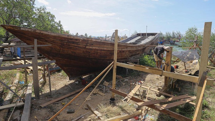 Pekerja menyelesaikan pembuatan kapal di kawasan galangan kapal nelayan Gampong Jawa, Banda Aceh, Aceh, Kamis (25/7/2024). Menurut pelaku usaha galangan kapal tradisional, pembuatan kapal nelayan berkapasitas 20-30 gross ton (GT) dengan biaya ratusan juta rupiah hingga miliaran rupiah itu membutuhkan waktu pengerjaan sekitar delapan bulan hingga satu tahun, tergantung ketersediaan bahan baku kayu. ANTARA FOTO/Khalis Surry