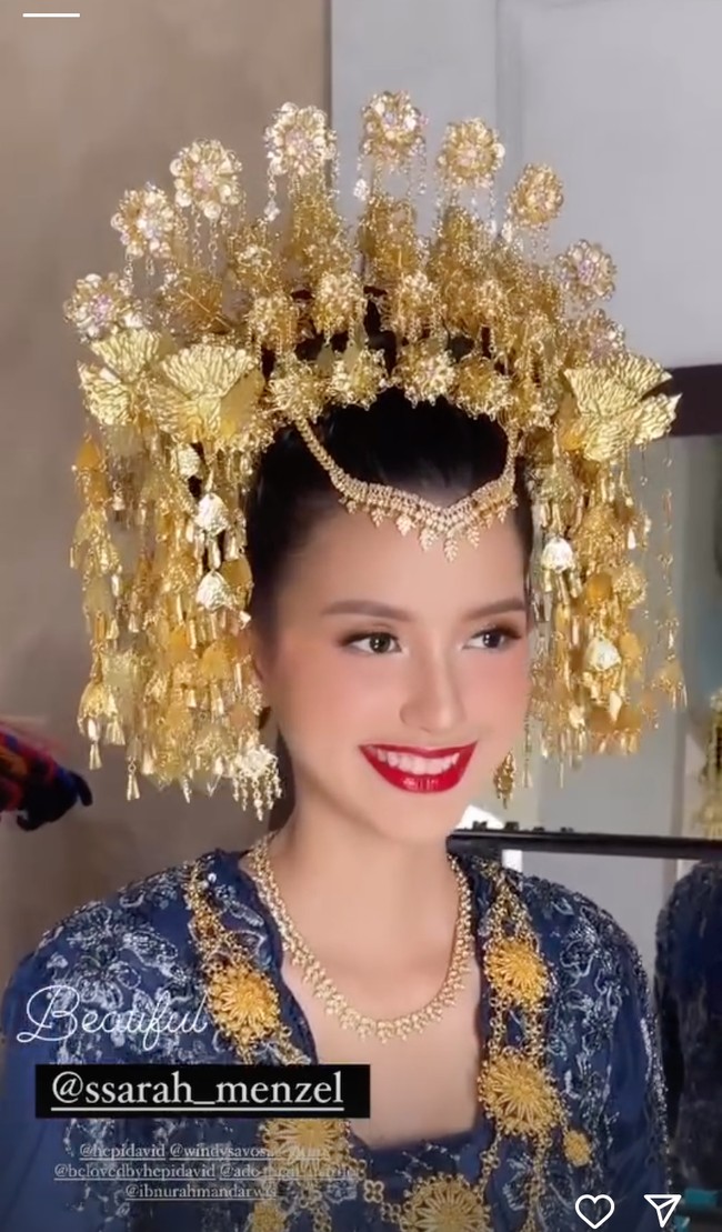 Kembali mempercayakan riasan wajahnya kepada MUA Hepi David, penampilannya kali ini terlihat lebih bold dengan lipstik merah. Namun pesonanya tak kalah menawan dari sebelumnya. Foto: Instagram/@ssarah_menzel/@anchawedding_