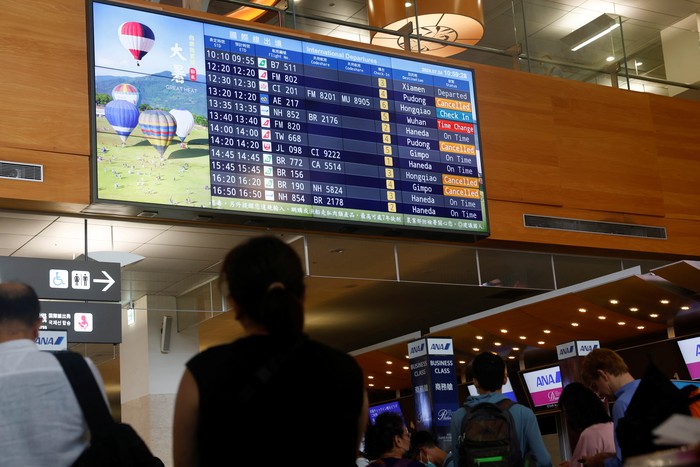 People wait in line near a screen displaying flight information at the international departures hall of the Taipei Songshan Airport as Typhoon Gaemi approaches in Taipei, Taiwan July 24, 2024. REUTERS/Carlos Garcia Rawlins