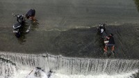 Warga mencuci sepeda motor di tepian Sungai Cileungsi, Desa Gunung Sari, Kabupaten Bogor, Jawa Barat, Kamis (25/7/2024).