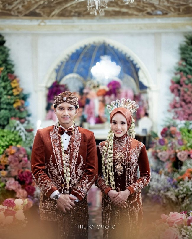 Chand Kelvin dan Dea Sahirah menikah dengan adat Jawa pada Minggu (7/7/2024). Dea tampil anggun dengan kebaya velvet panjang model kutu baru berwarna coral di akad pernikahan. Sementara itu, Chand Kelvin terlihat gagah dengan beskap coral yang dipadu kain cokelat lengkap dengan blankon. Foto: Instagram