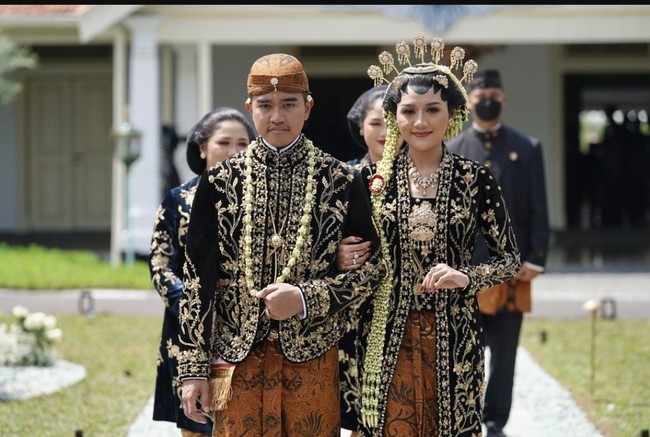 Erina Gudono dinikahi Kaesang Pangarep pada 10 Desember 2022. Erina terlihat memesona dalam balutan busana adat Jawa di berbagai rangkaian prosesi pernikahan. Salah satunya, saat Erina memakai baju pengantin adat Jawa Solo Putri di tasyakuran pernikahan. Ia mengenakan kebaya hitam berhias bordiran emas yang dipadu kain batik. Foto: Instagram