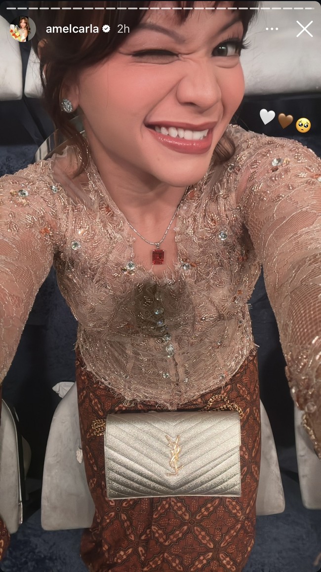 Amel Carla tampil cantik dengan kebaya coklat yang dipadukan dengan sepasang anting dan kalung dengan batu berwarna merah. Ia juga melengkapi penampilannya dengan clutch berwarna silver. Foto: Instagram
