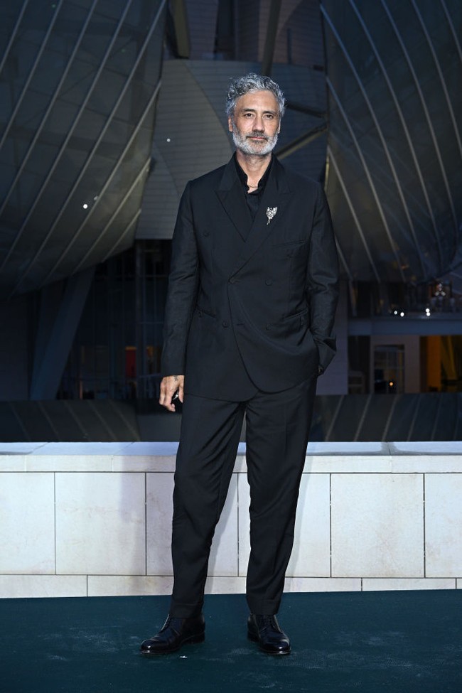 Sutradara dan aktor Taika Waititi tampil serba hitam dengan setelan jas dan kemeja. Foto: Getty Images for LVMH x Vogue x /Kristy Sparow