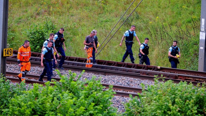 SNCF railway workers and law enforcement officers walk at the site where vandals targeted France's high-speed train network with a series of coordinated actions that brought major disruption, ahead of the Paris 2024 Olympics opening ceremony, in Croisilles, northern France  July 26, 2024. REUTERS/Brian Snyder REFILE - CORRECTING FROM 'POLICE OFFICERS' TO 'LAW ENFORCEMENT OFFICERS'  .