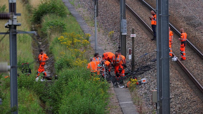 SNCF railway workers and law enforcement officers walk at the site where vandals targeted France's high-speed train network with a series of coordinated actions that brought major disruption, ahead of the Paris 2024 Olympics opening ceremony, in Croisilles, northern France  July 26, 2024. REUTERS/Brian Snyder REFILE - CORRECTING FROM 'POLICE OFFICERS' TO 'LAW ENFORCEMENT OFFICERS'  .