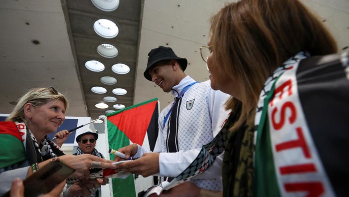 Palestinian athletes and pro-Palestinian supporters pose for a photo at the Charles de Gaulle airport ahead of the Paris 2024 Olympic Games, in Paris, France July 25, 2024. REUTERS/Yves Herman