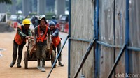 Sebagian pekerja tampak lalu-lalang mengangkut material bangunan di lokasi proyek.  