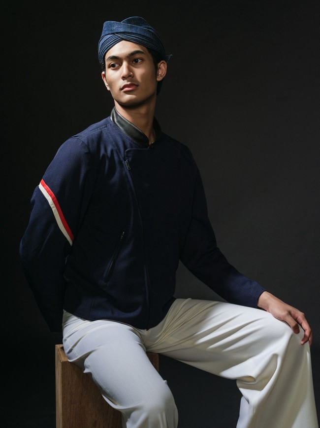 Material yang menyerupai denim untuk beskap memberikan kesan modern, ditambah lagi dengan kehadiran garis merah-putih sebagai aksentuasi asimetris di lengan kanan. Tidak ketinggalan aksesori tambahan berupa blangkon kulit hitam dan selop senada yang menciptakan kesan edgy pada penampilan para pria. (Foto: Dok. Davy Linggar)