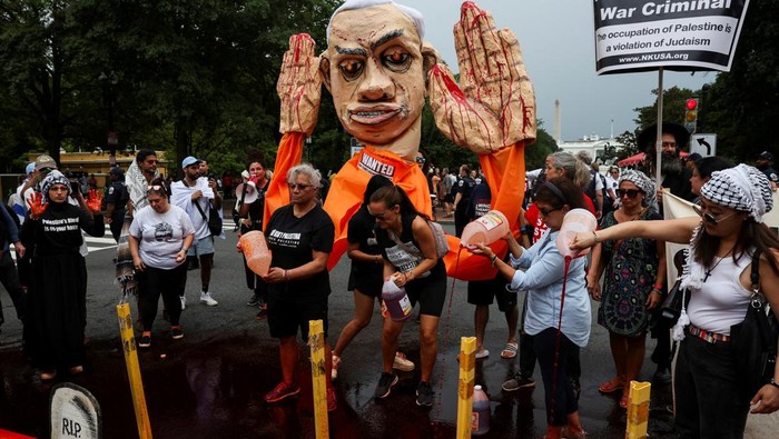 People pour fake blood, as demonstrators gather during a pro-Palestinian rally on the day Israeli Prime Minister Benjamin Netanyahu is scheduled to hold White House meetings with U.S. President Joe Biden and Vice President Kamala Harris, at Lafayette Square Park in Washington, D.C., U.S., July 25, 2024. REUTERS/ Umit Bektas