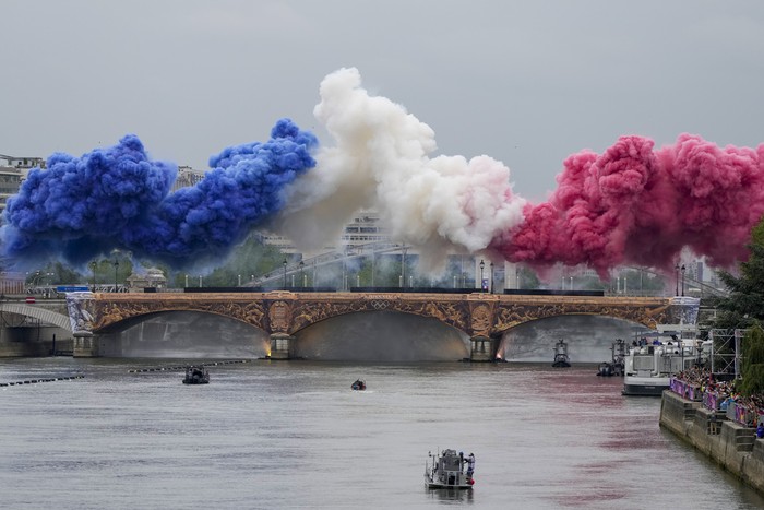 Ceremonial smoke in the colors of the France flag appear over the Seine River in Paris, France, during the opening ceremony of the 2024 Summer Olympics, Friday, July 26, 2024. (AP Photo/Matthias Schrader)