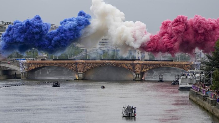 Ceremonial smoke in the colors of the France flag appear over the Seine River in Paris, France, during the opening ceremony of the 2024 Summer Olympics, Friday, July 26, 2024. (AP Photo/Matthias Schrader)