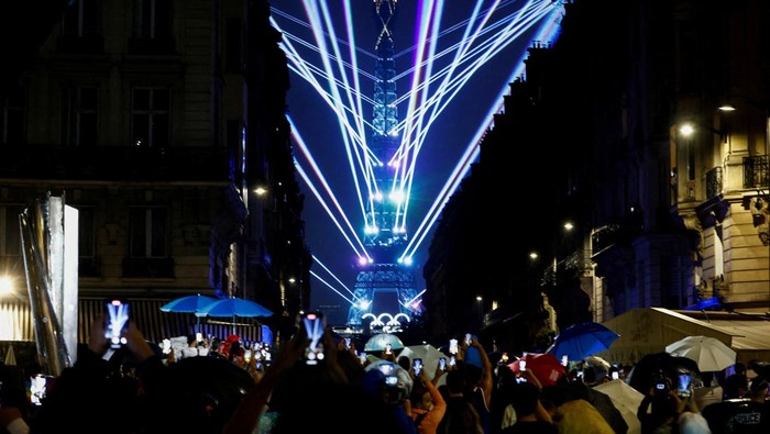 Paris 2024 Olympics - Paris, France - July 26, 2024. Spectators look at the light show at the Eiffel Tower during the opening ceremony of the Paris 2024 Olympics REUTERS/Gonzalo Fuentes