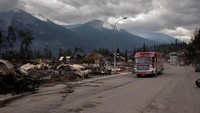 Sebuah mobil pemadam kebakaran berjalan melewati blok permukiman yang hancur di Jasper, Alberta, Kanada, pada Jumat (26/7/2024).