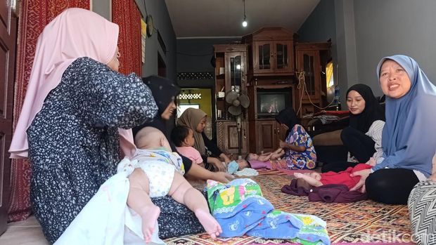 Mak Arsih sedang memijat bayi