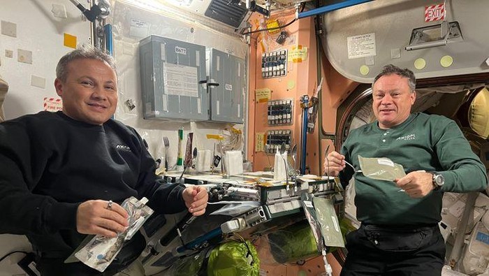 Anggota kru Ax-3 Alper Gezeravcı dan Michael López-Alegría sedang bersantap di atas ISS pada 2023.