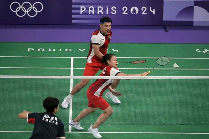 Indonesias Pitha Haningtyas Mentari hits a shot next to Rinov Rivaldy in their mixed doubles badminton group stage match against South Korea during the Paris 2024 Olympic Games at Porte de la Chapelle Arena in Paris on July 27, 2024. (Photo by Arun SANKAR / AFP)