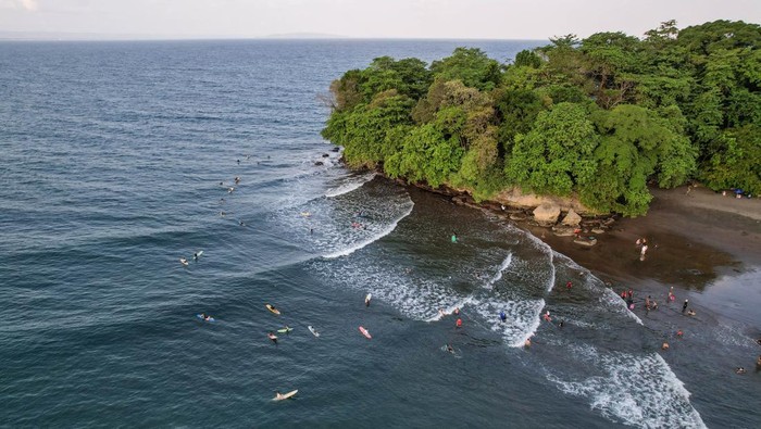Serunya Taklukkan Ombak di Pantai Batukaras Foto udara sejumlah wisatawan beselancar di Pantai Batukaras, Kecamatan Cijulang, Kabupaten Pangandaran, Jawa Barat, Sabtu (27/7/2024). Pantai Batukaras yang telah dikenal sebagai destinasi wisata selancar ombak atau