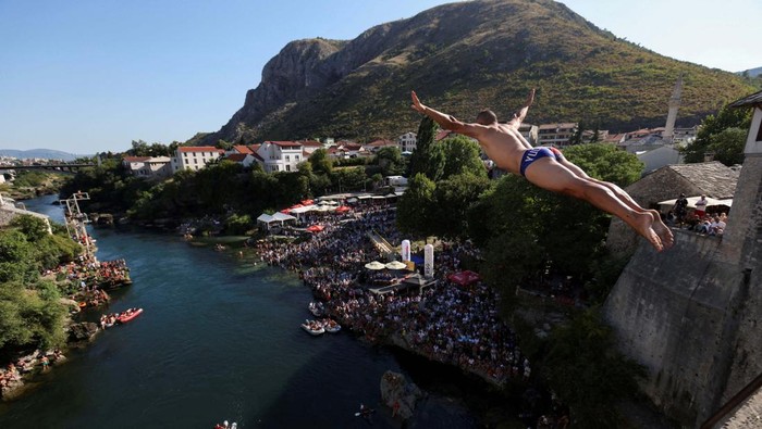 Aksi Melompat dari Jembatan Tua Bosnia yang Bikin Merinding A high diver jumps from the arch of the Old Bridge during 458th edition of the traditional diving competition in Mostar, Bosnia and Herzegovina, July 28, 2024. REUTERS/Amel Emric