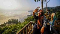 Pengunjung berswafoto dengan latar belakang negeri di atas awan di Citorek, Lebak, Banten, Senin (29/7/2024).   