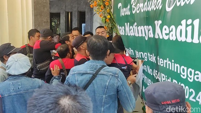 Massa berupaya menerobos masuk PN Surabaya sembari membawa karangan bunga