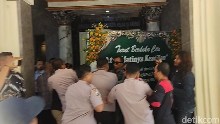 Massa berupaya menerobos masuk PN Surabaya sembari membawa karangan bunga