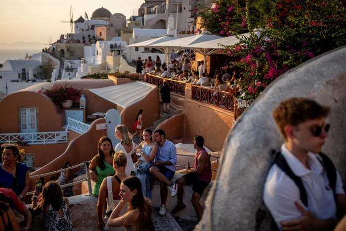 A couple poses for a photo as tourists line up to take a photo as they view Santorini’s famed sunset, at Santorini, Greece, July 25, 2024. REUTERS/Alkis Konstantinidis