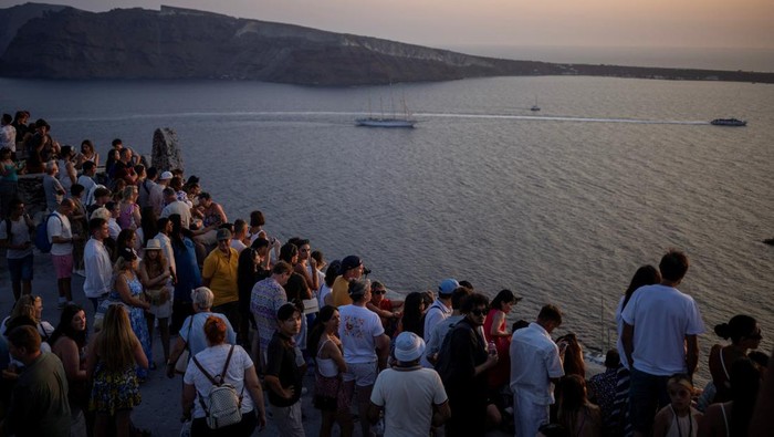A couple poses for a photo as tourists line up to take a photo as they view Santorini’s famed sunset, at Santorini, Greece, July 25, 2024. REUTERS/Alkis Konstantinidis
