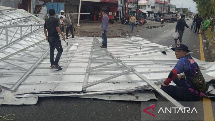 Petugas BPBD melakukan pembersihan bagian atap gedung milik pemerintah daerah yang terbang saat terjangan angin kencang, di ruas Jalan Nasional Meulaboh, Kabupaten Aceh Barat, Ahad (28/7/2024) petang. (ANTARA/HO-Dok. BPBD Aceh Barat)