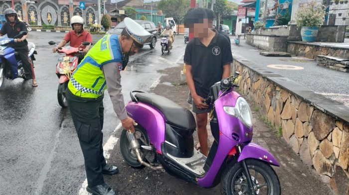 Polisi menilang seorang pelajar yang menggunakan klapot brong di Karangasem, Bali, Minggu (28/7/2024).
