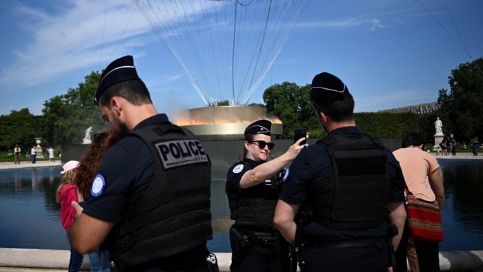 Paris 2024 Olympics - Paris, France - July 28, 2024 People pose for pictures in front of the Olympic cauldron during the Olympics REUTERS/Dylan Martinez